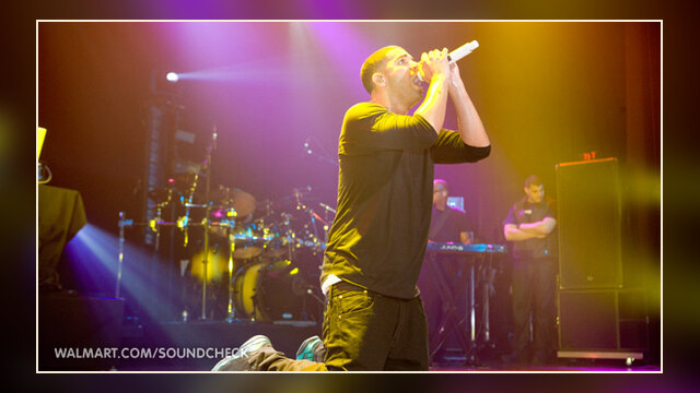 Drake performing live at a Walmart Soundcheck event, singing into a microphone.