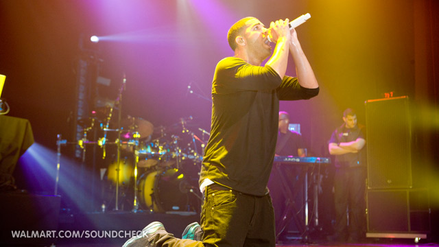 Drake performing live at a Walmart Soundcheck event, singing into a microphone.