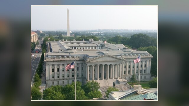 Photograph of the U.S. Treasury building in Washington, D.C., with the Washington Monument visible in the background.