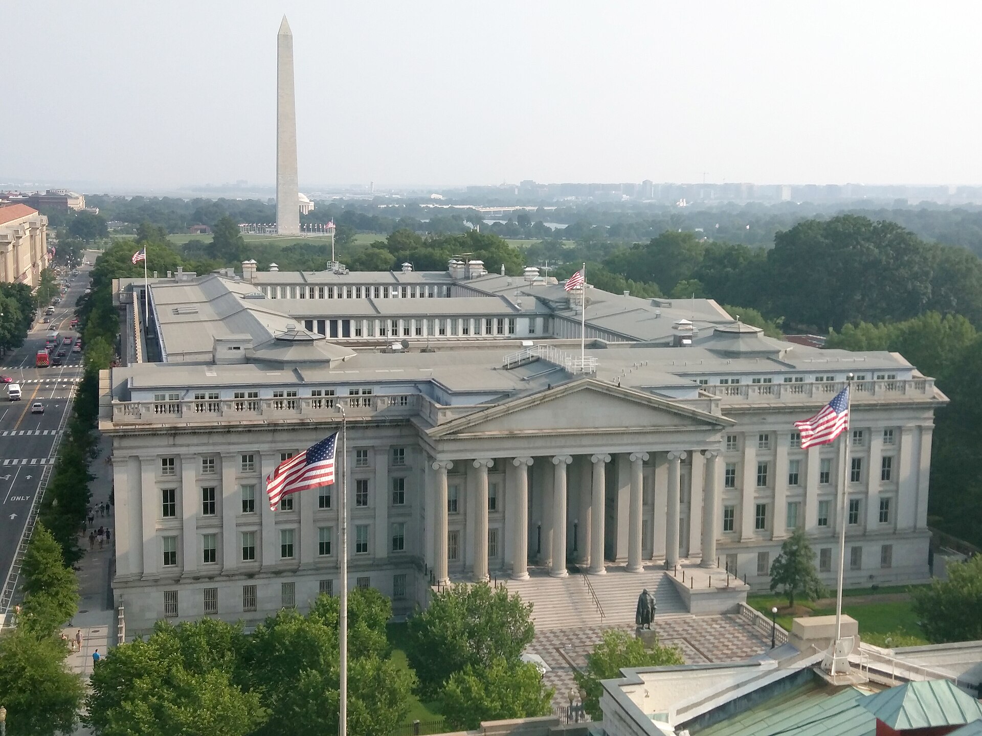 Photograph of the U.S. Treasury building in Washington, D.C., with the Washington Monument visible in the background.